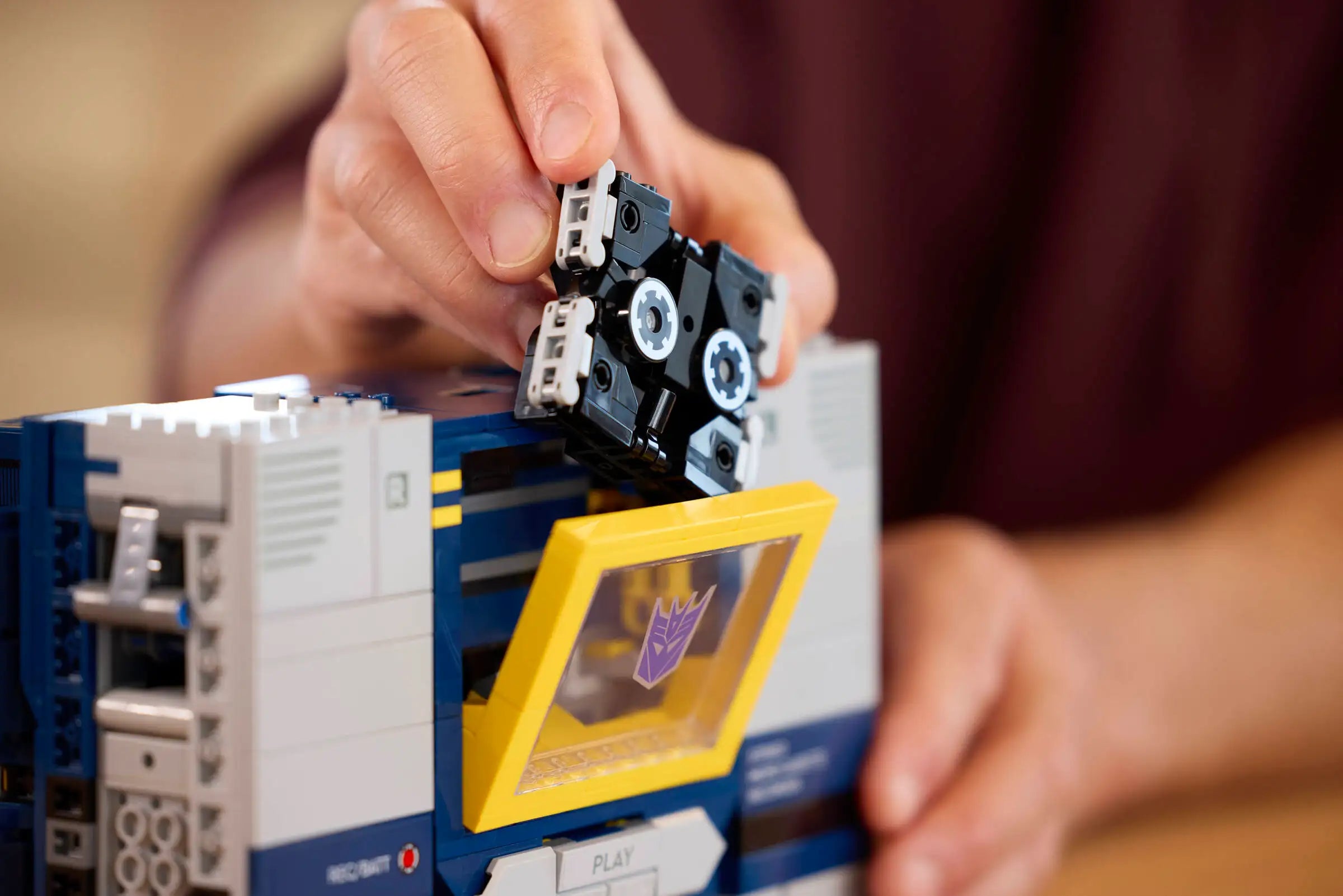 Person assembling LEGO 10358 Transformers: Soundwave with a focus on the hands and components.