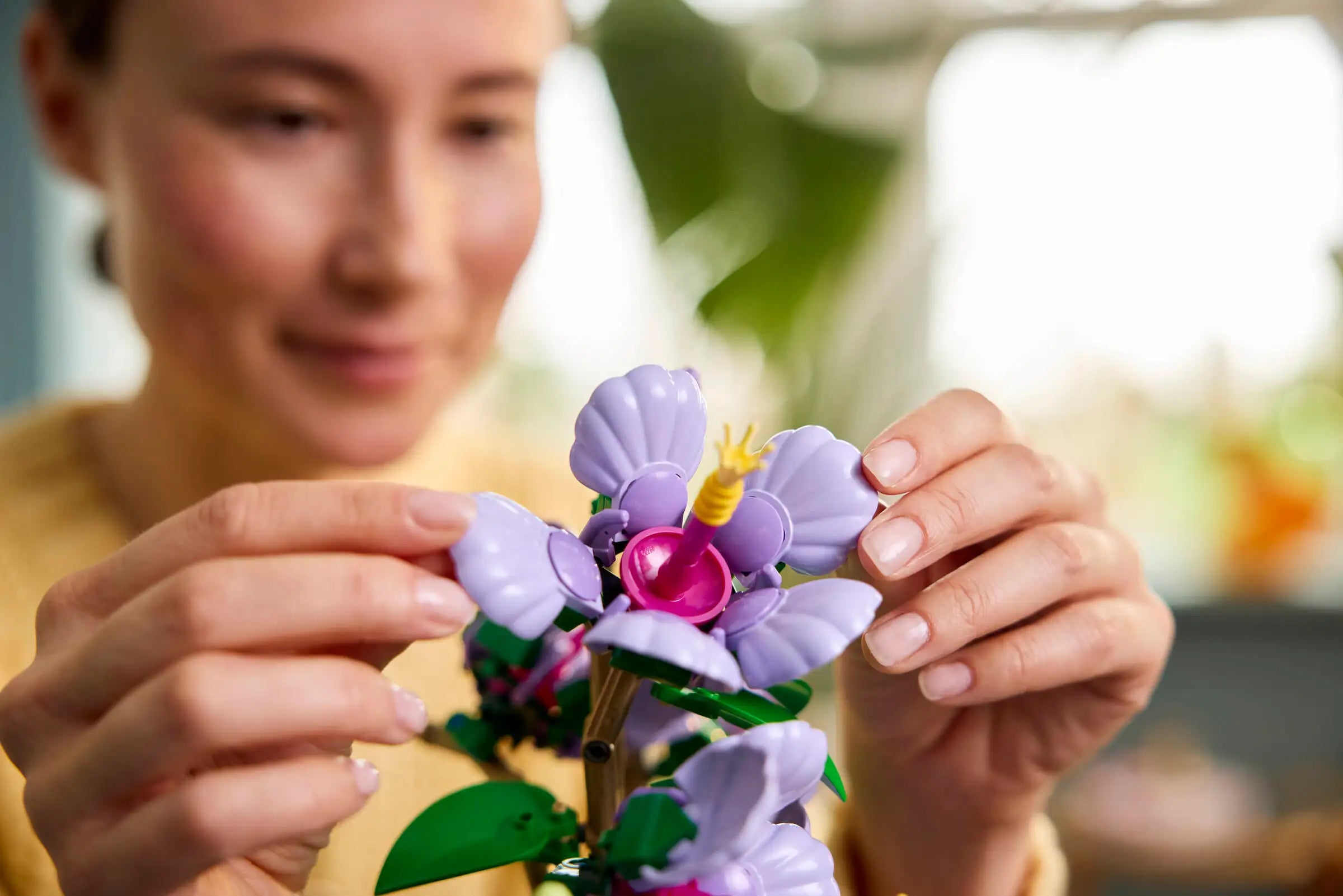 Person holding a small purple flower toy with a blurred background