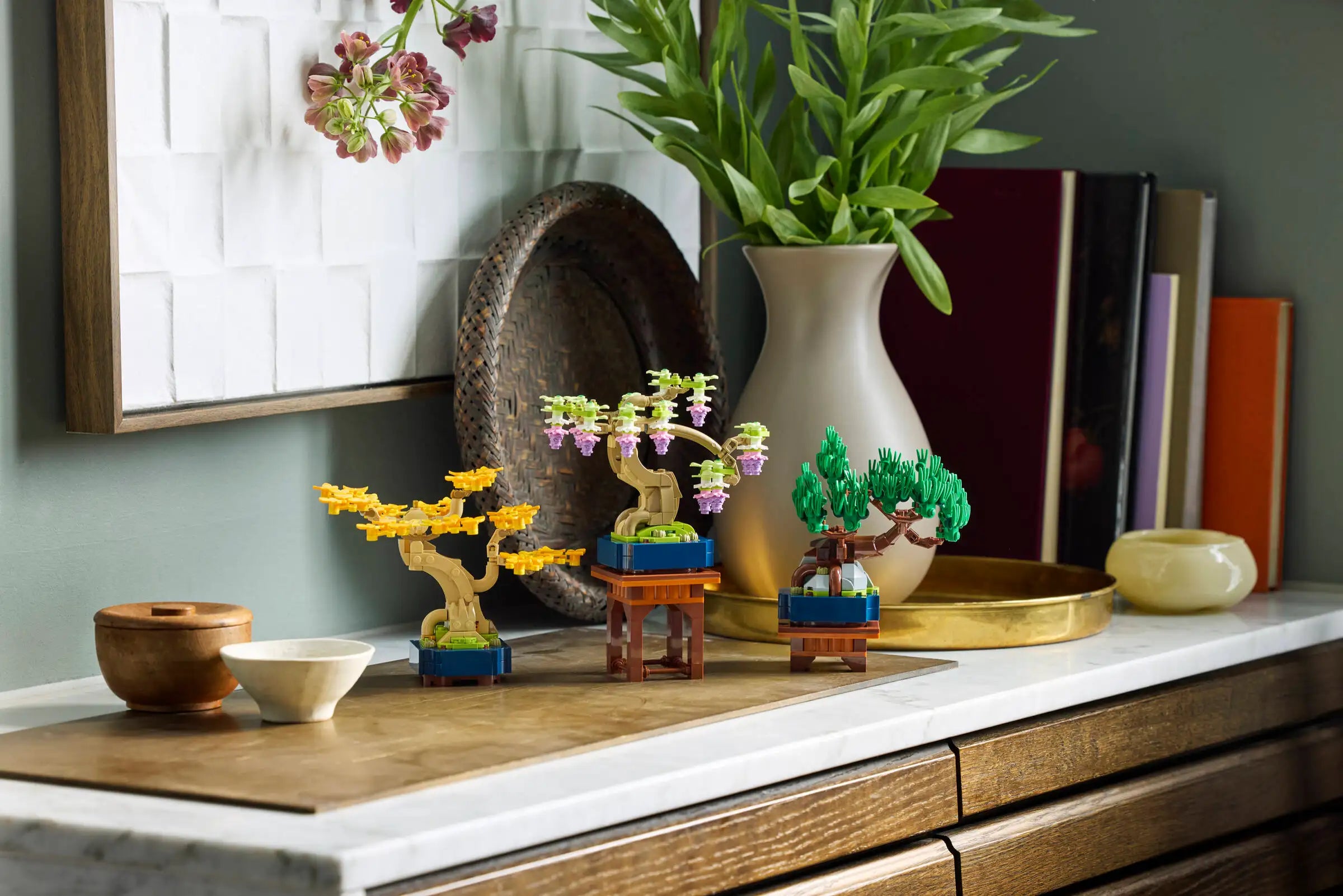 Decorative LEGO 10373 Mini Bonsai Trees on a shelf with a vase and books in the background.