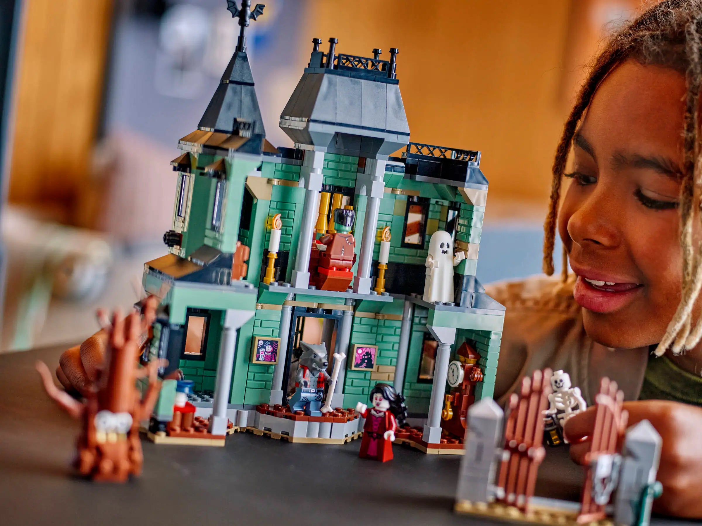 Child playing with a detailed LEGO 31167 Haunted Mansion set on a table.