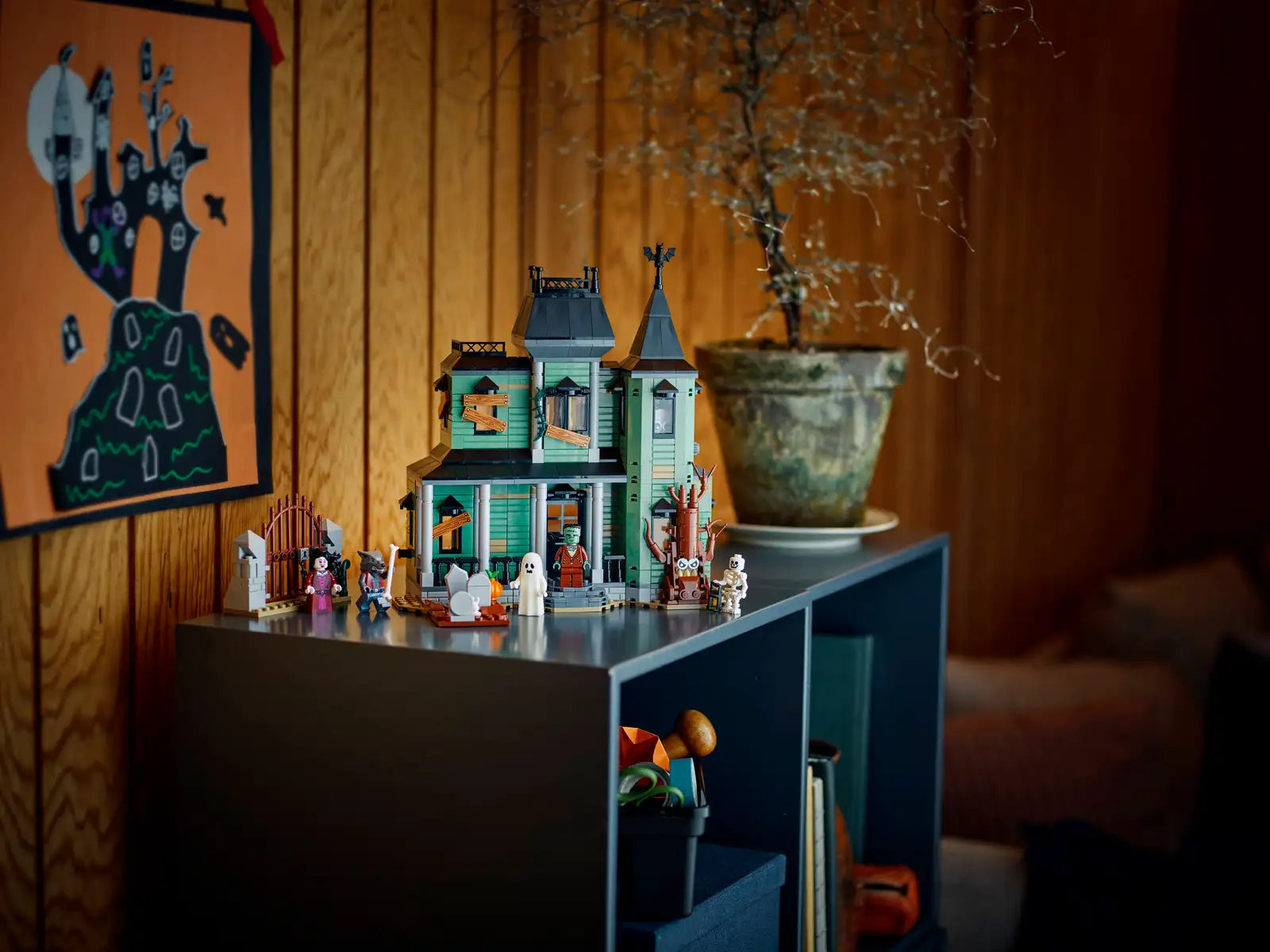 LEGO 31167 Haunted Mansion set on a shelf with decorative items against a wooden wall.