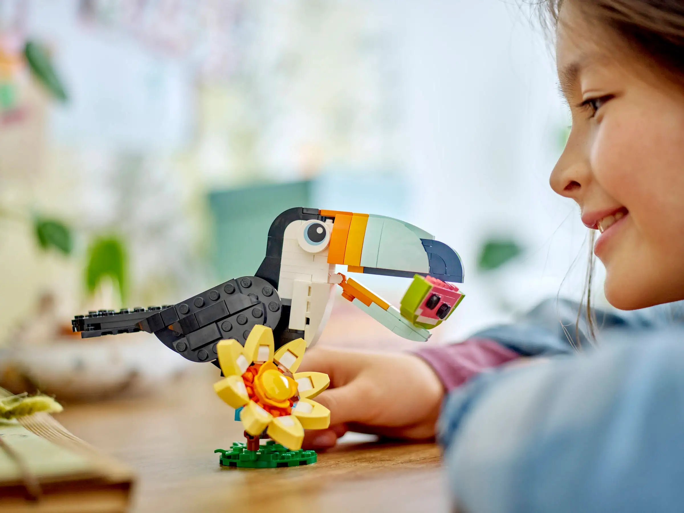 Child playing with a LEGO 31173 Tropical Toucan set on a wooden table