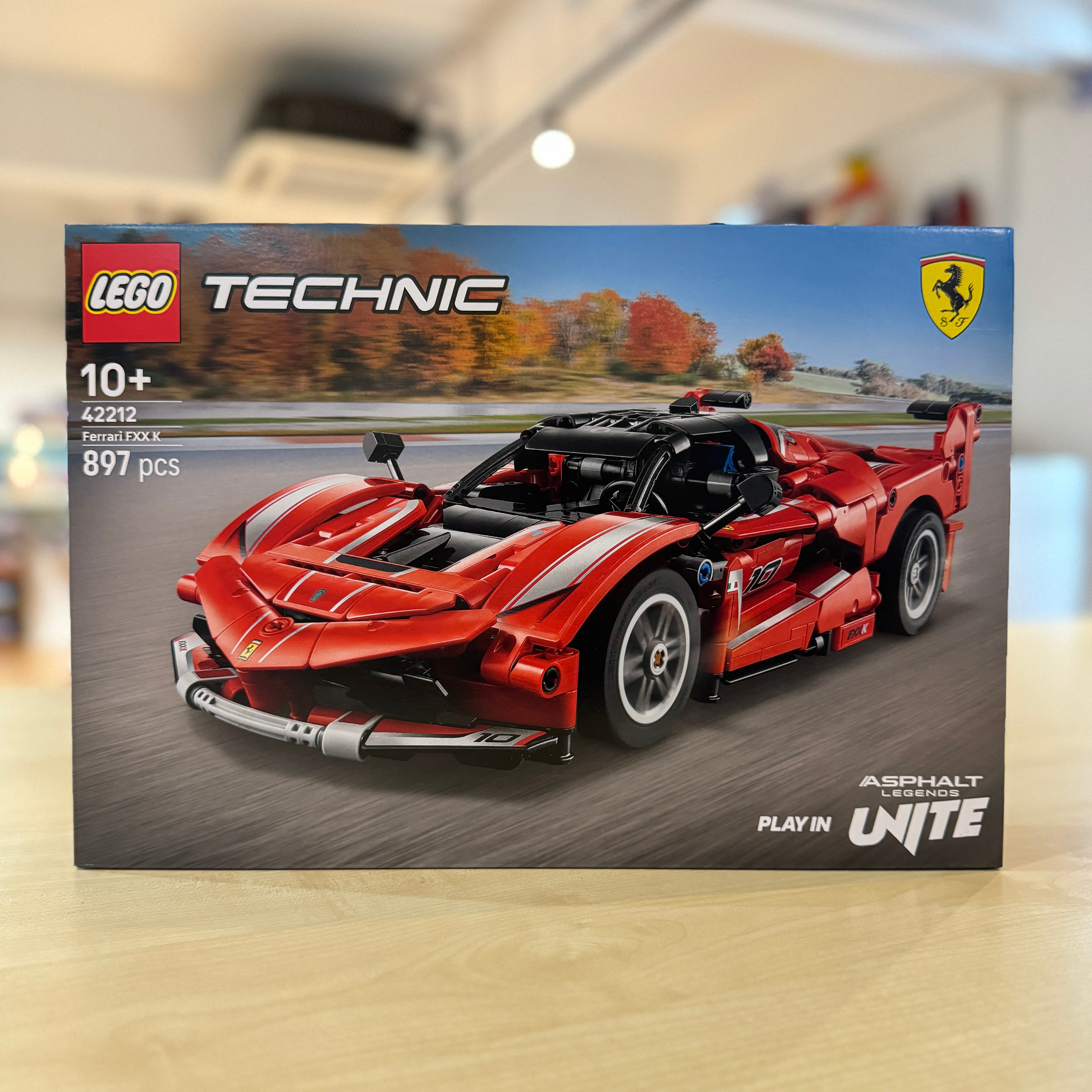 LEGO 42212 Ferrari FXX K model kit packaging on a wooden surface with blurred background
