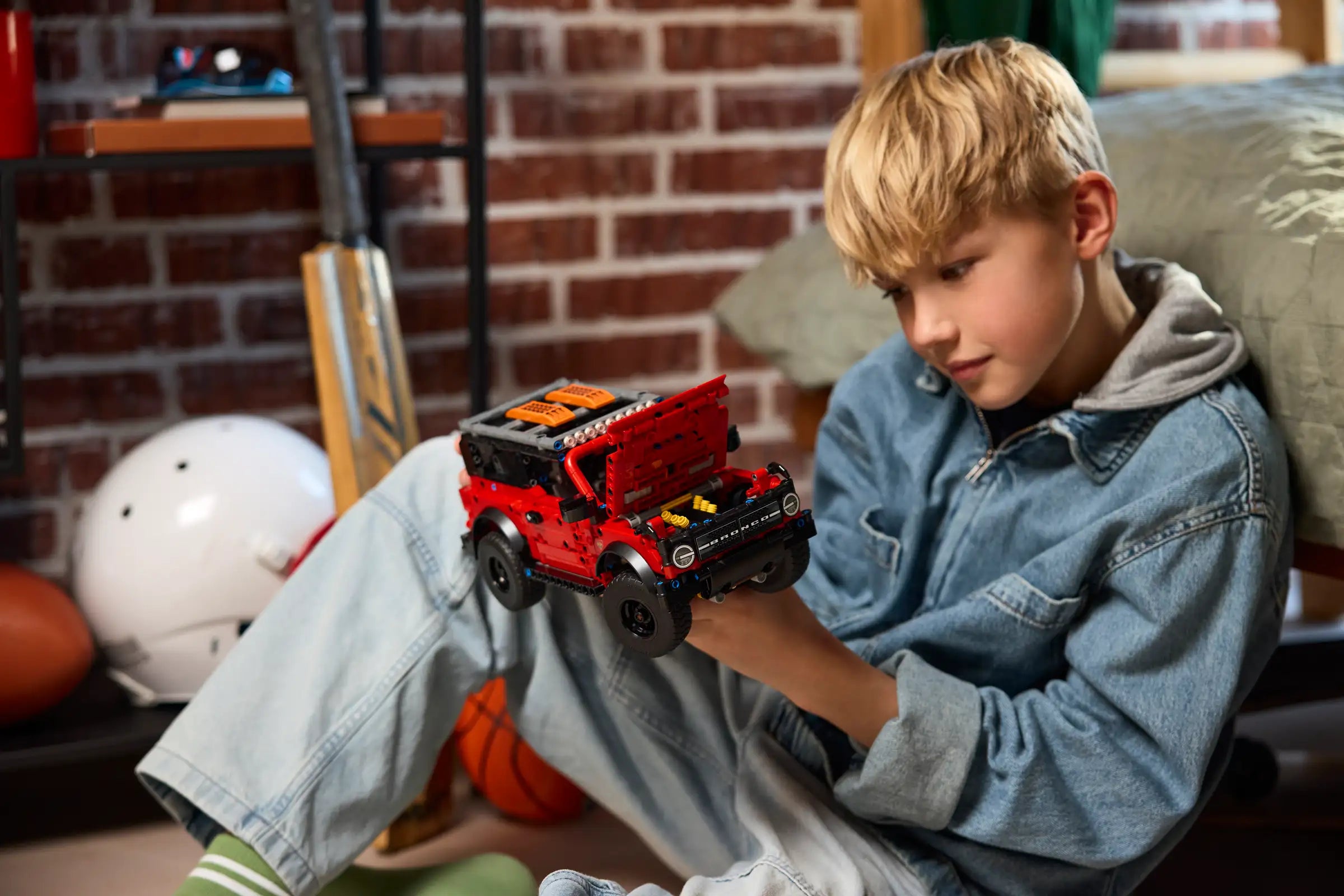 Child playing with a LEGO 42213 Ford Bronco SUV in a casual indoor setting