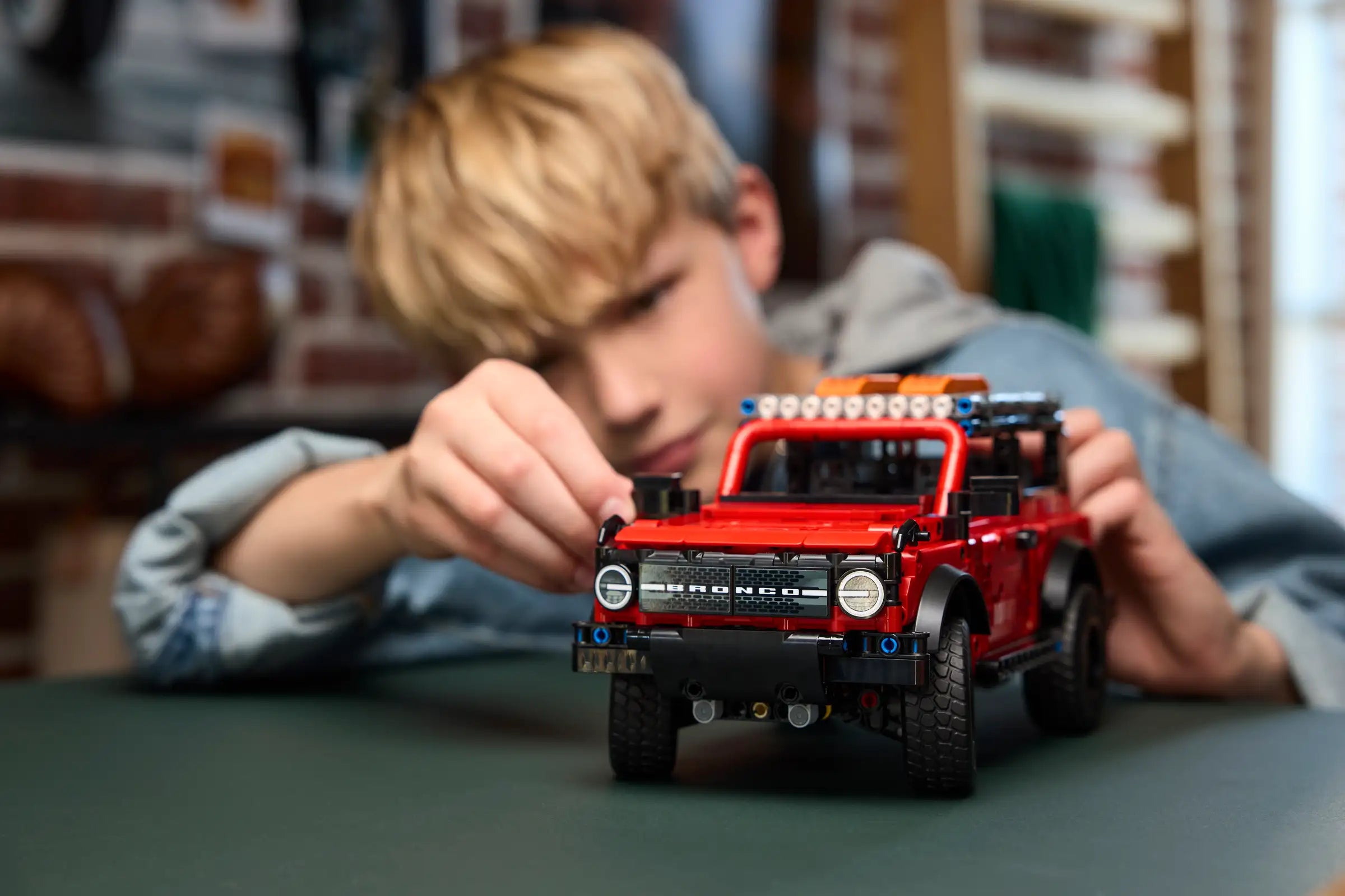 Child playing with a LEGO 42213 Ford Bronco SUV on a table