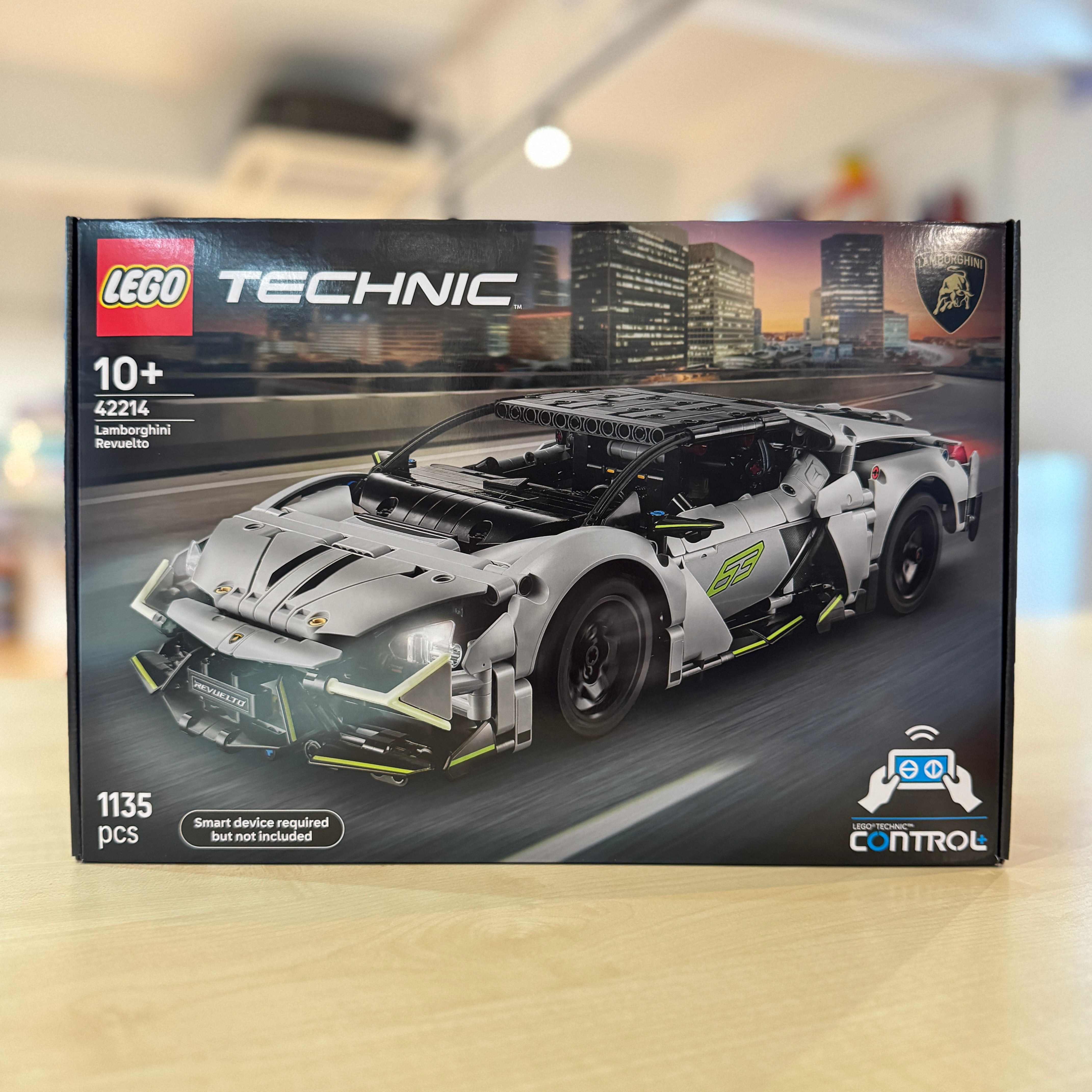 LEGO 42214 Lamborghini Revuelto building set packaging on a blurred cityscape background