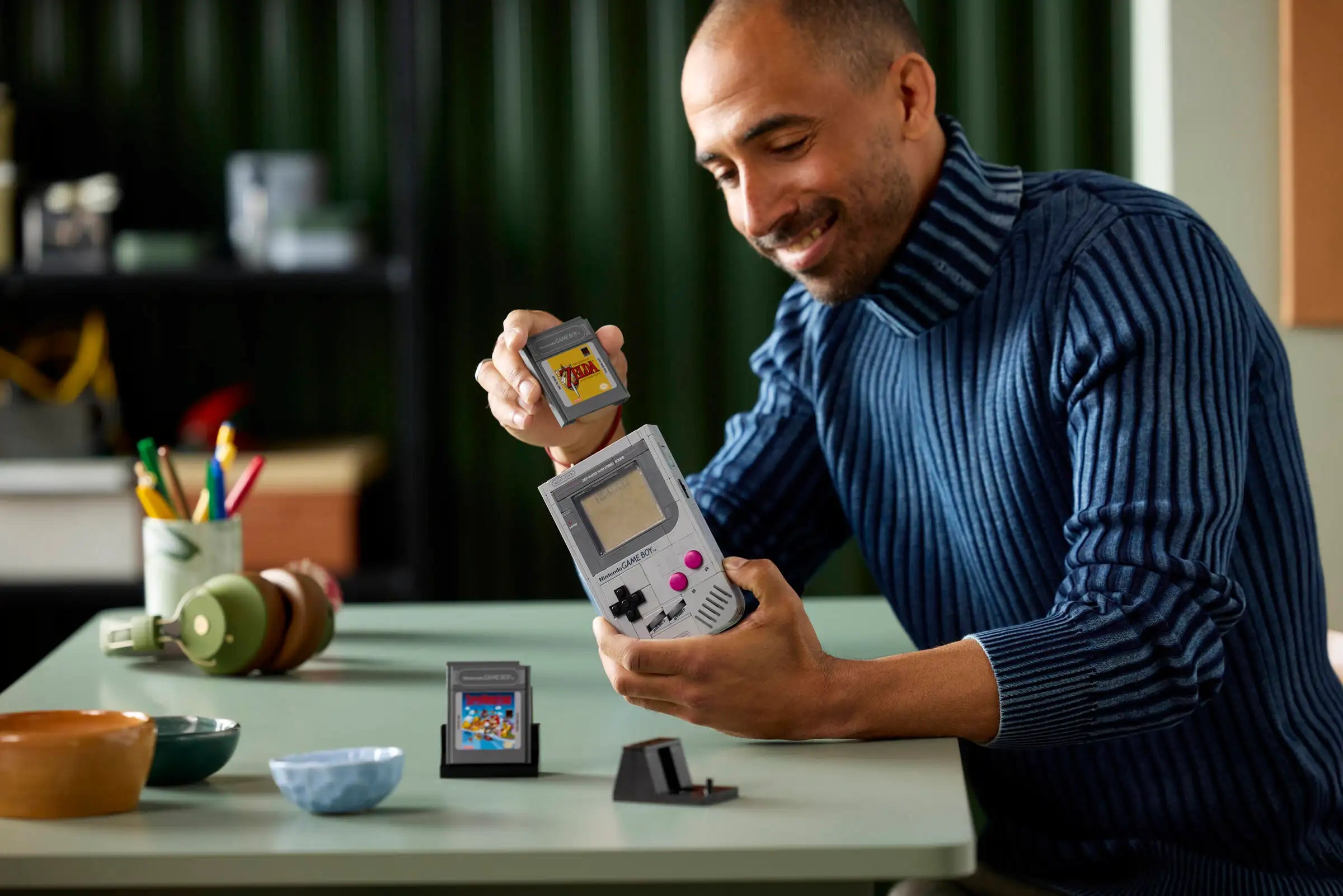 Man holding a LEGO 72046 Game Boy and Game Boy Game in an indoor setting