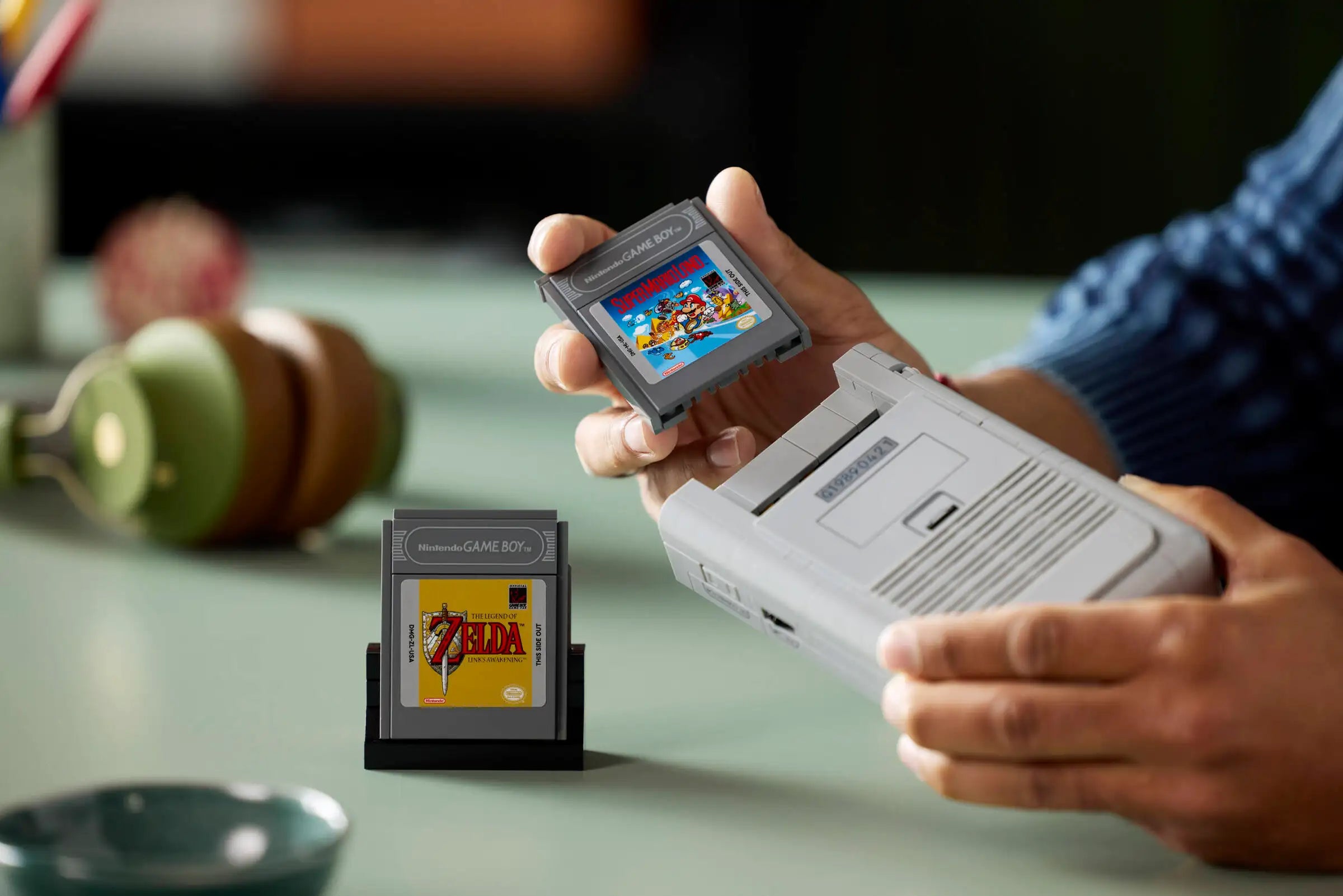 Person holding a LEGO 72046 Game Boy with a 'The Legend of Zelda' cartridge.