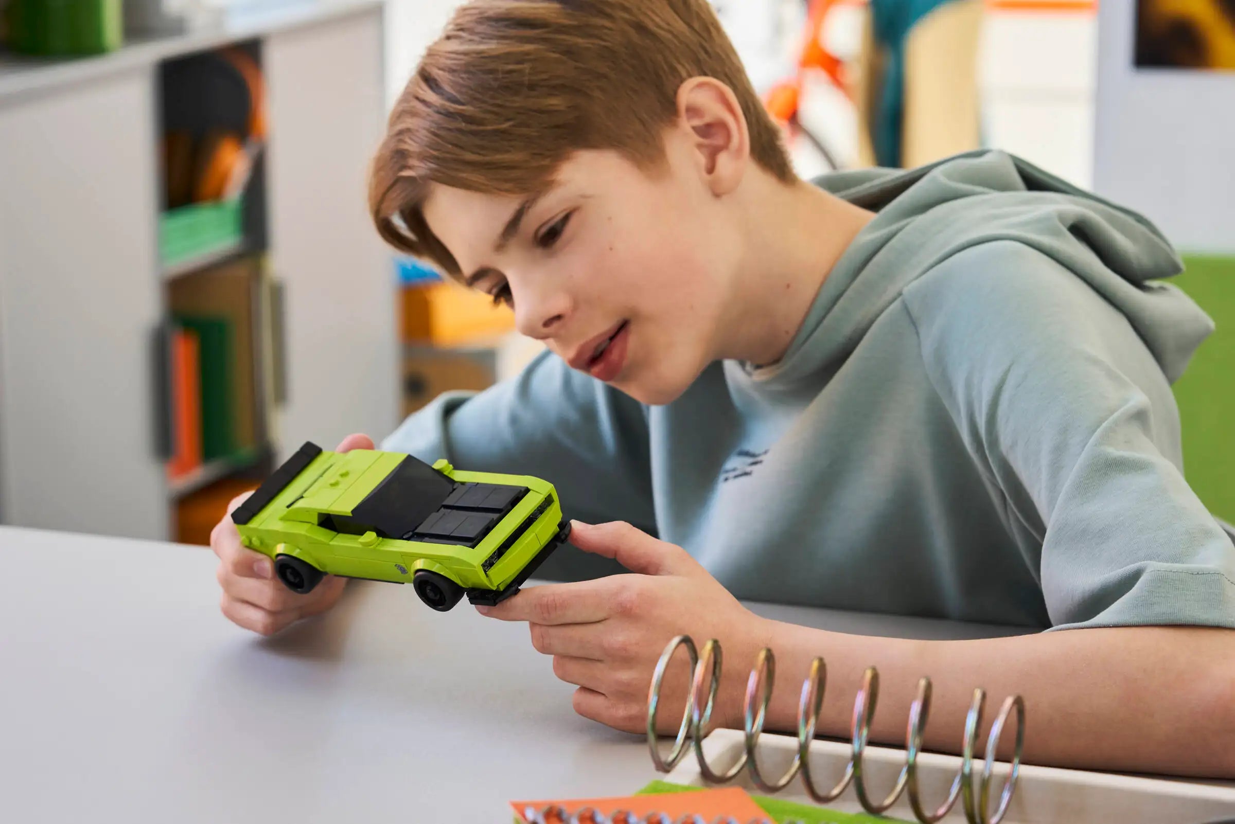 Child playing with LEGO 77237 Dodge Challenger SRT Hellcat car in a classroom setting