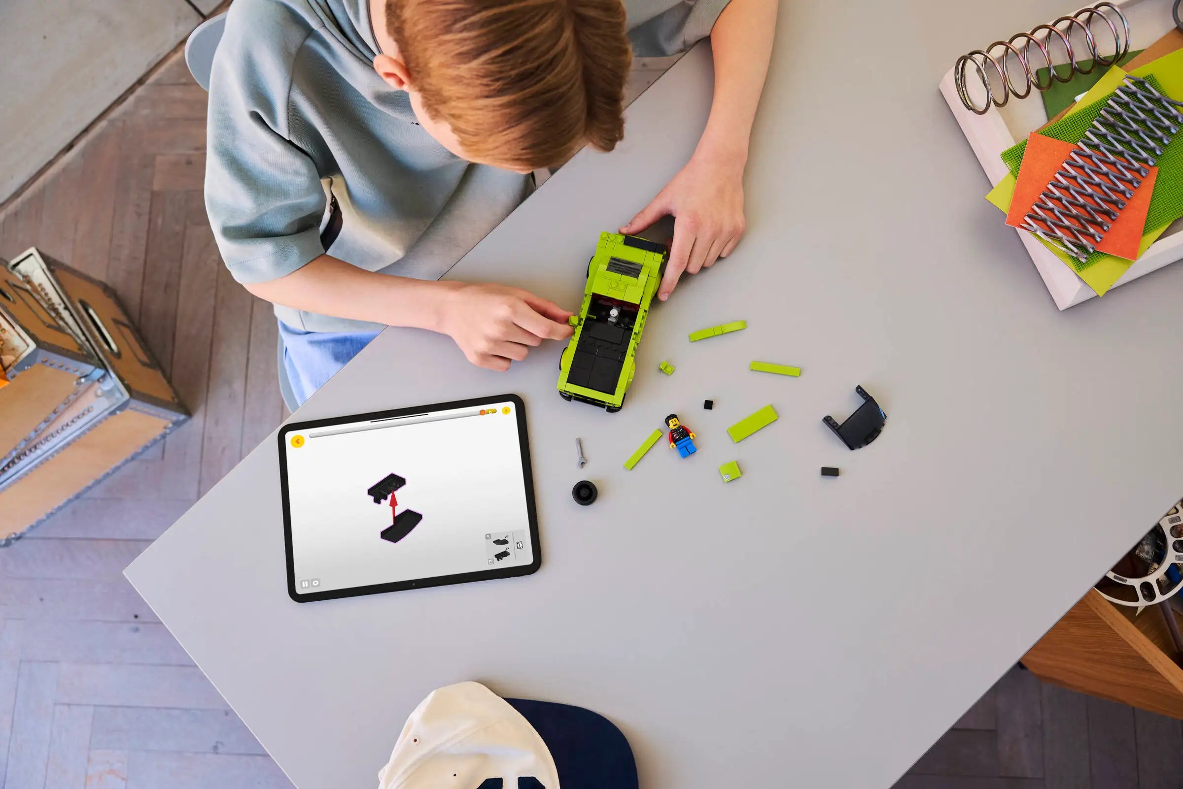 Child playing with LEGO 77237 Dodge Challenger SRT Hellcat and a tablet on a table