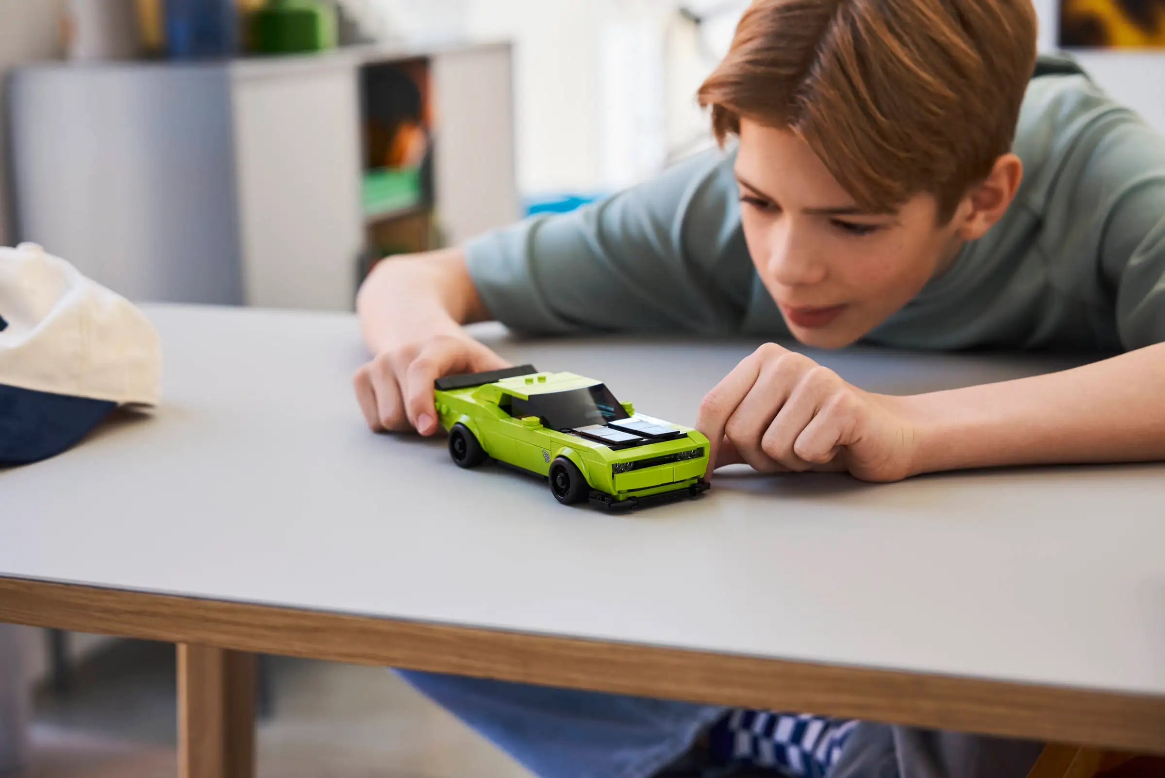 Child playing with LEGO 77237 Dodge Challenger SRT Hellcat on a table