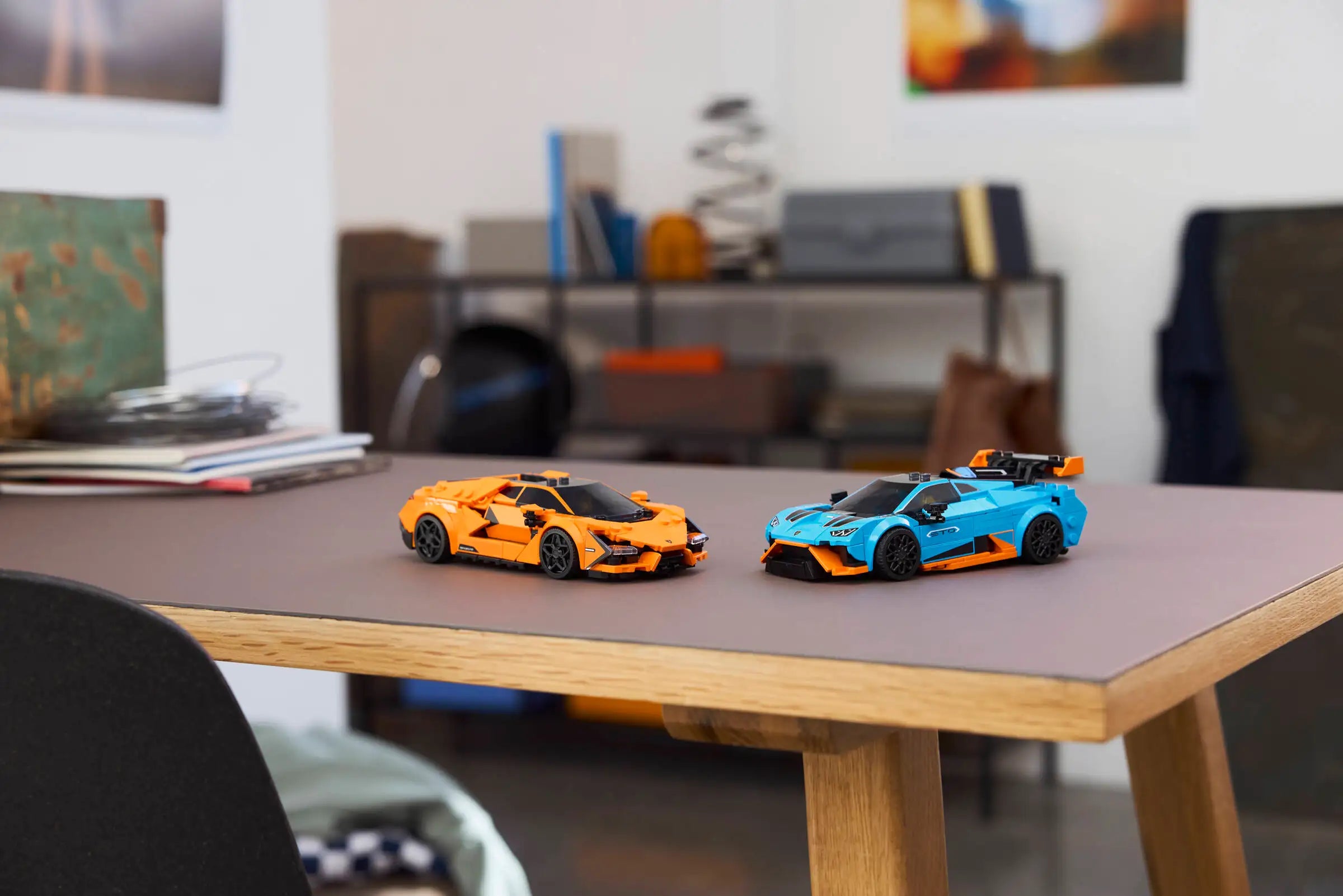 LEGO 77238 Lamborghini Revuelto & Lamborghini Huracán STO - Two toy cars, one orange and one blue, on a wooden table with a blurred indoor background.