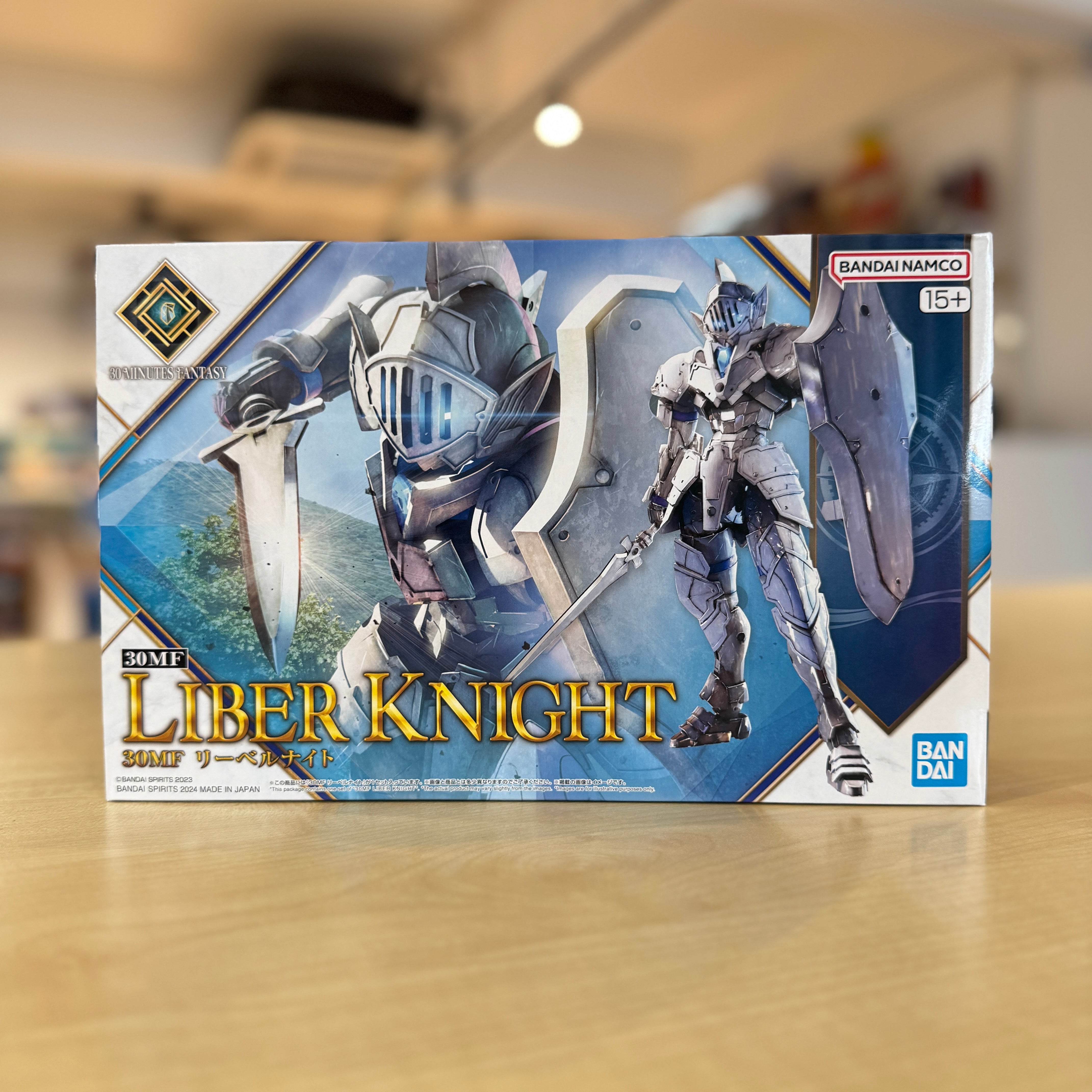 Box of Liber Knight toy figure with Bandai logo on a blurred indoor background