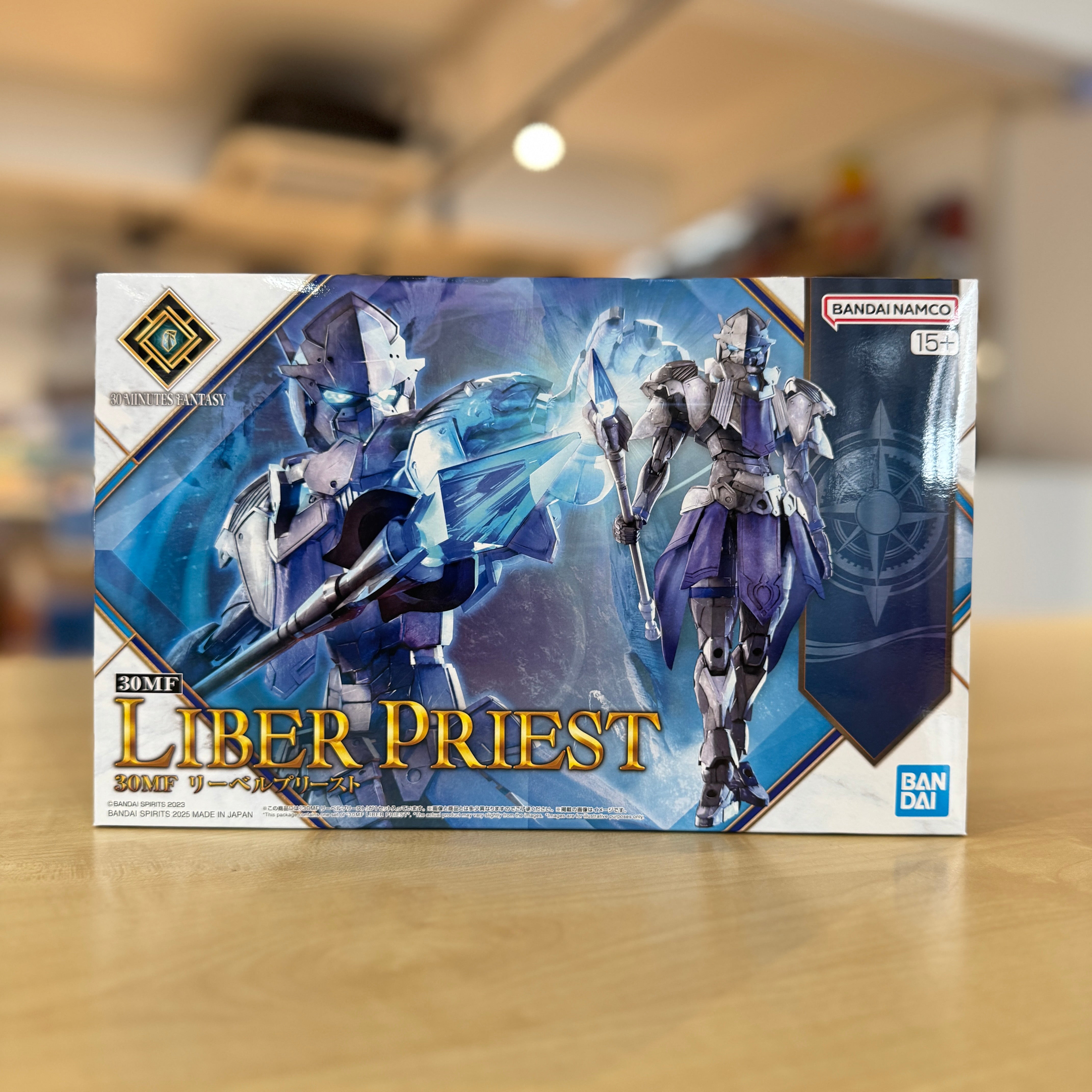 Box of '30MF Liber Priest' model kit by Bandai Namco on a wooden surface with a blurred background.