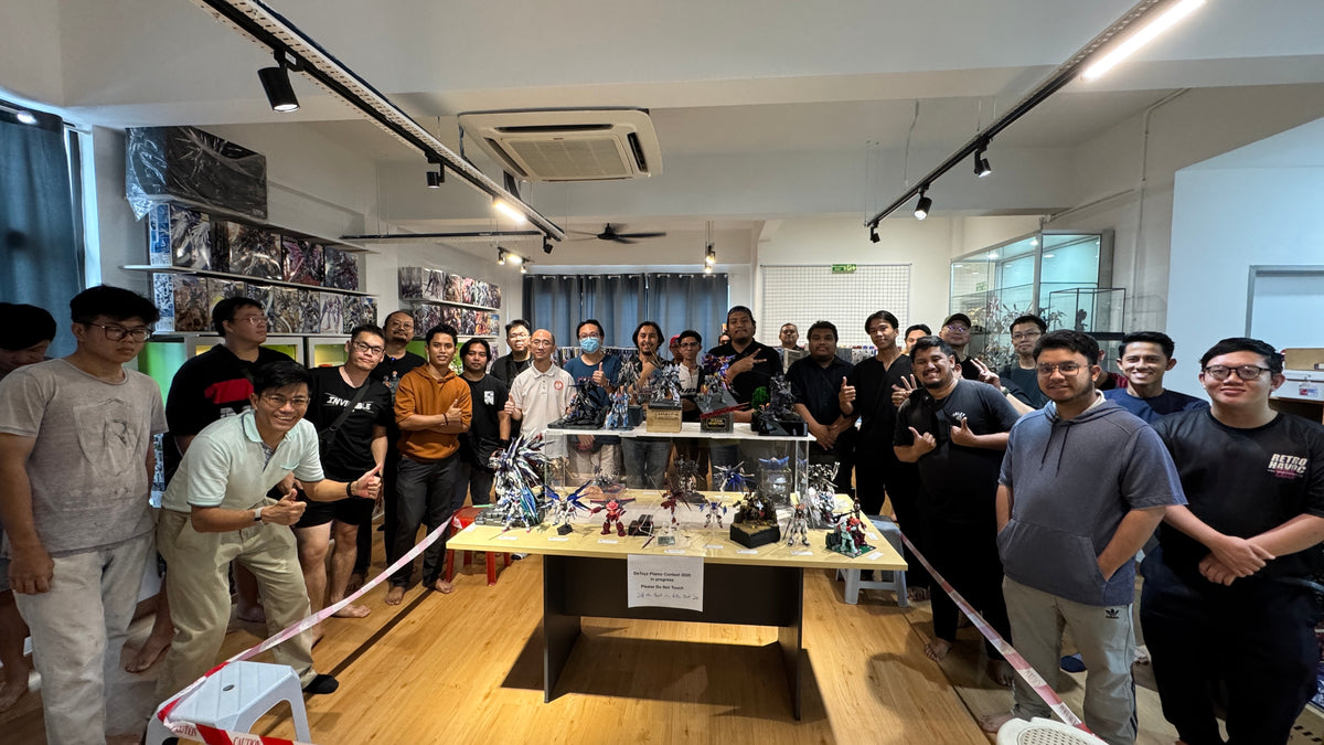 Group of people gathered around a table with a model or display, in an indoor setting - DeToyz Plamo Contest 2025 Result announcement.