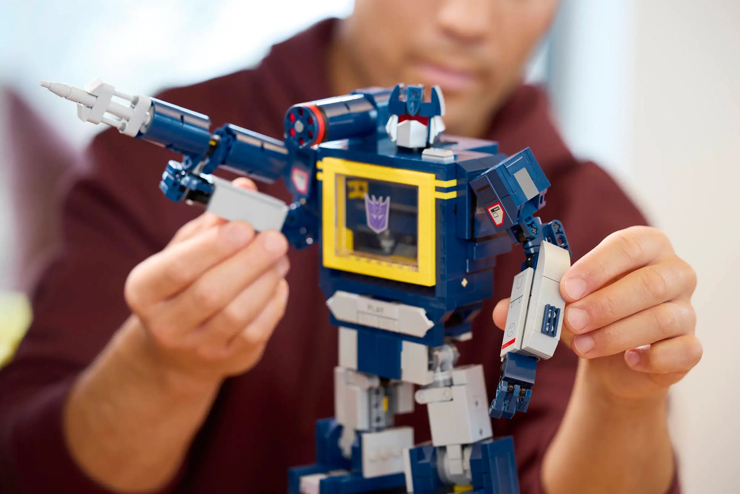Person holding a LEGO 10358 Transformers: Soundwave in front of a blurred background