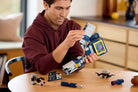Man assembling a LEGO 10358 Transformers: Soundwave set on a table with various LEGO pieces around