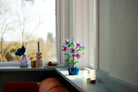 Decorative LEGO 10372 Hibiscus on a windowsill with candles and a candle holder.
