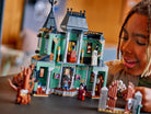 Child playing with a detailed LEGO 31167 Haunted Mansion set on a table.