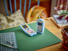Two miniature models of vintage phones on a green cutting mat with a wooden surface and chair in the background - LEGO 31174 Retro Telephone