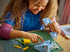 Child playing with a LEGO 31174 Retro Telephone on a table with tools