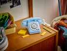 Vintage-style blue phone on a wooden surface with stationery items - LEGO 31174 Retro Telephone