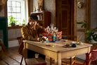 Person playing with LEGO 75640 The Baratie Floating Restaurant at a wooden table in a room with plants and furniture.
