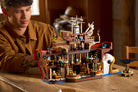 Man playing with a detailed LEGO 75640 The Baratie Floating Restaurant model made of building blocks.