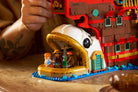 Person playing with a detailed LEGO 75640 The Baratie Floating Restaurant model of a ship on a wooden surface
