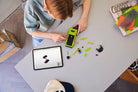 Child playing with LEGO 77237 Dodge Challenger SRT Hellcat and a tablet on a table
