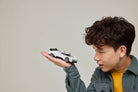 Child holding a LEGO 77240 Bugatti Centodieci car against a plain background